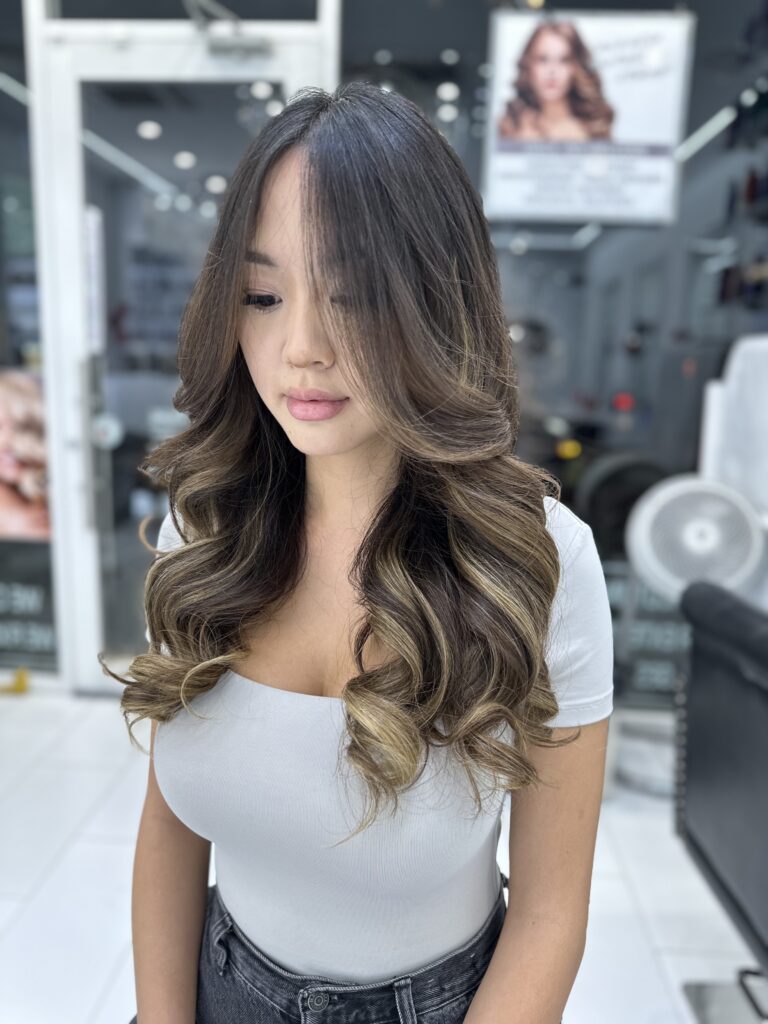Long brunette hair styled in soft waves with lighter highlights